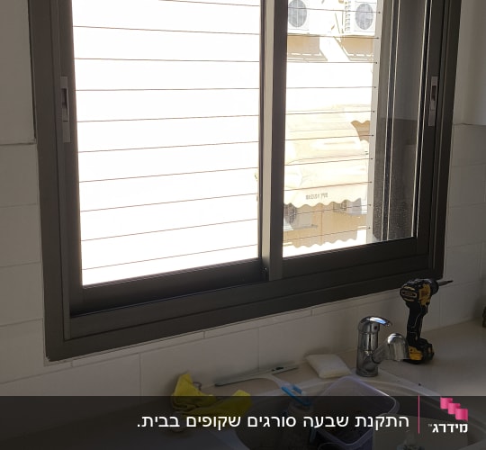 חלון אלומיניום מעל כיור במטבח עם כלים